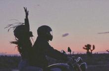 Хлопець і дівчина на мотоциклі на фоні заходу сонця